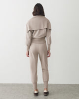 Person facing away, wearing matching pants and top in a studio setting.