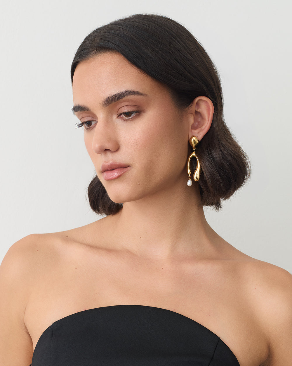 Person wearing drop earrings and a strapless top.