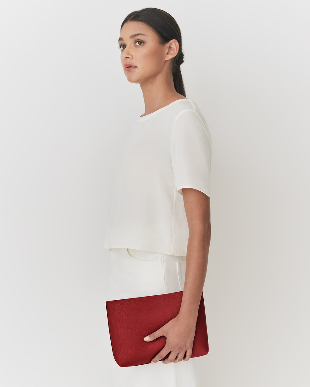 Person standing holding a large clutch bag.
