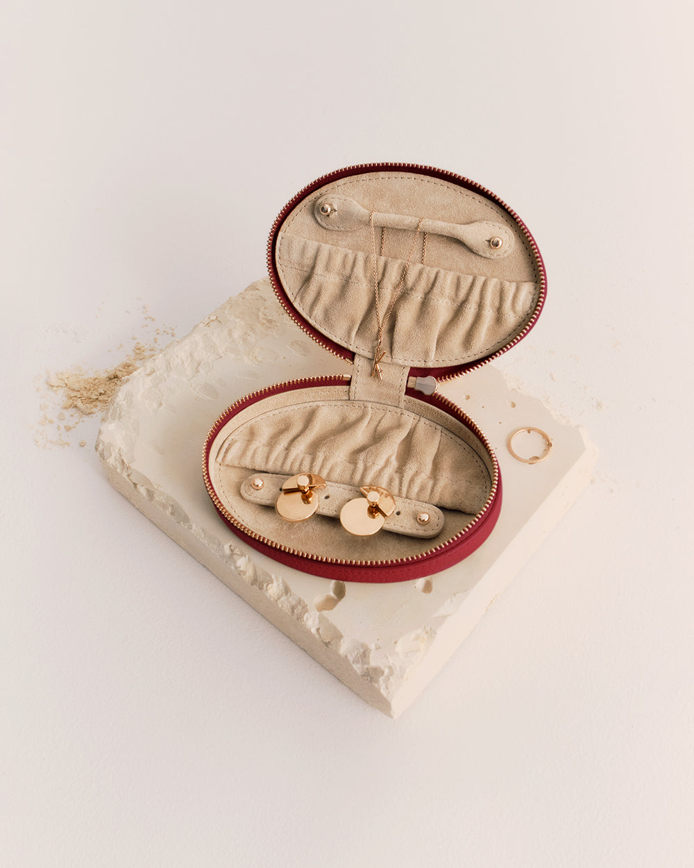 Oval jewelry case with rings on a textured surface.