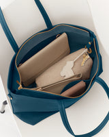 Open travel bag containing two wallets, a notebook, and a set of keys.