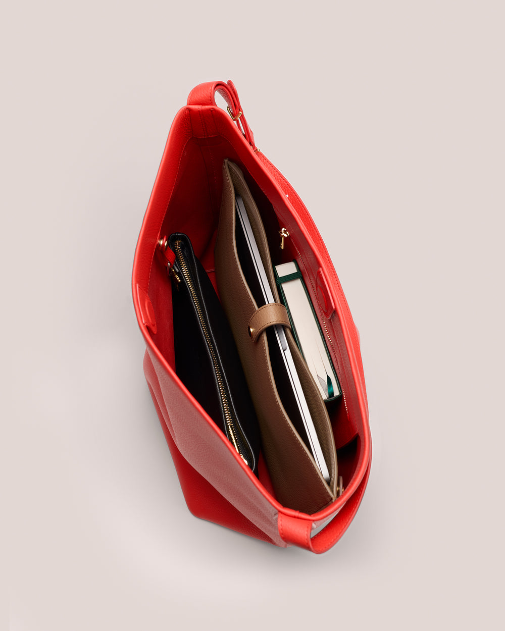Open handbag with various items inside, including a notebook and a zippered pouch.