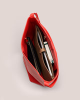 Open handbag with various items inside, including a notebook and a zippered pouch.