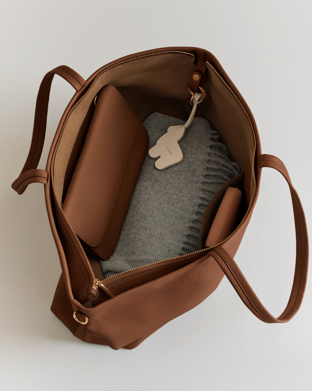 Open handbag with a wallet, fabric item, and a keychain inside.