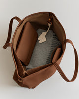 Open handbag with a wallet, fabric item, and a keychain inside.