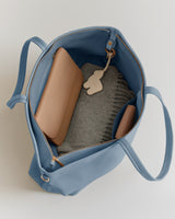 Open travel bag with purse and sweater inside.