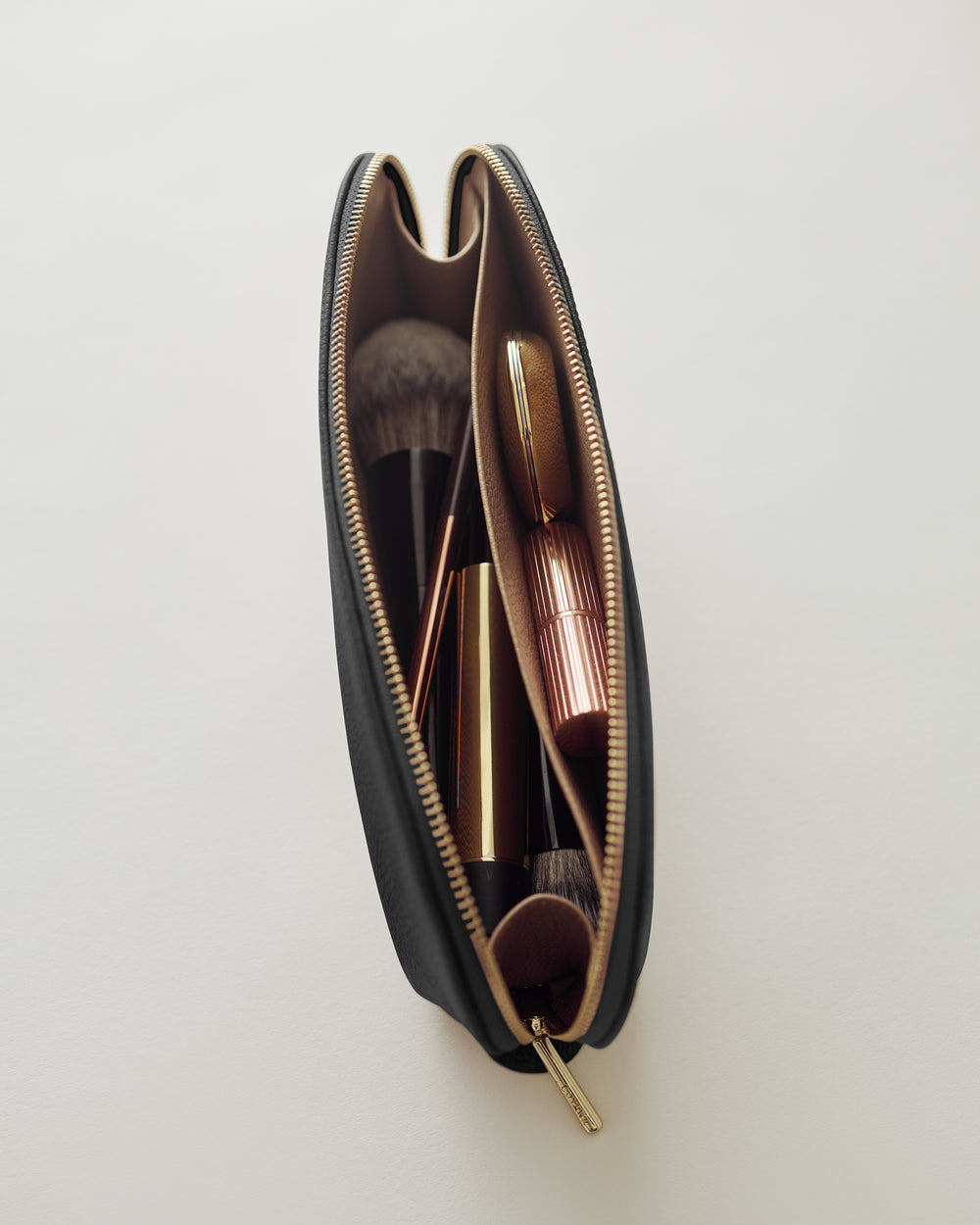 Open makeup bag with brushes and cosmetics inside.