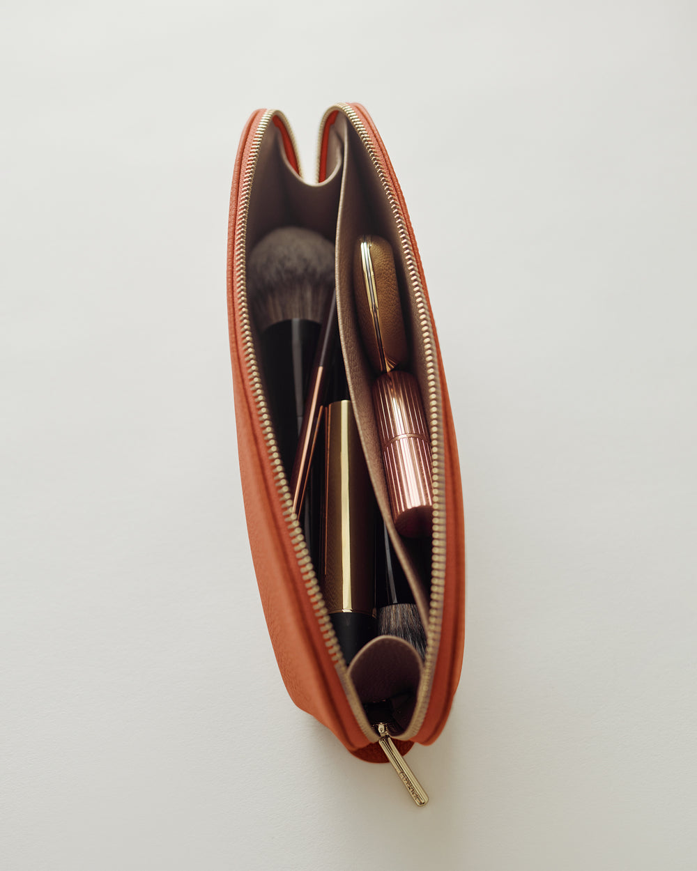 Makeup brushes and cosmetics in a zippered pouch.
