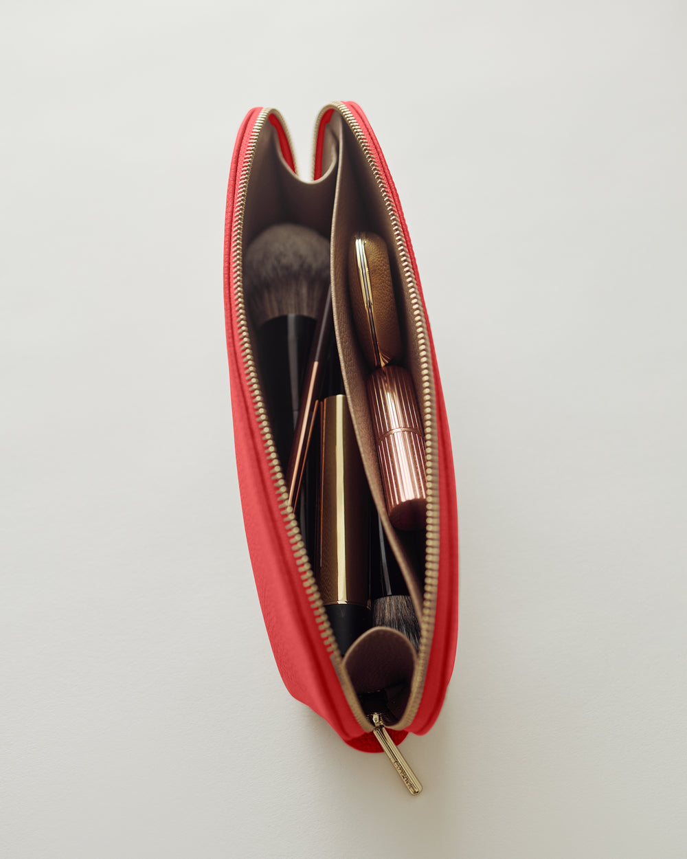Makeup brushes and a lipstick inside an open cosmetic pouch.