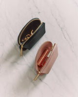 Two small zippered pouches on a marble surface, each holding cosmetic products.