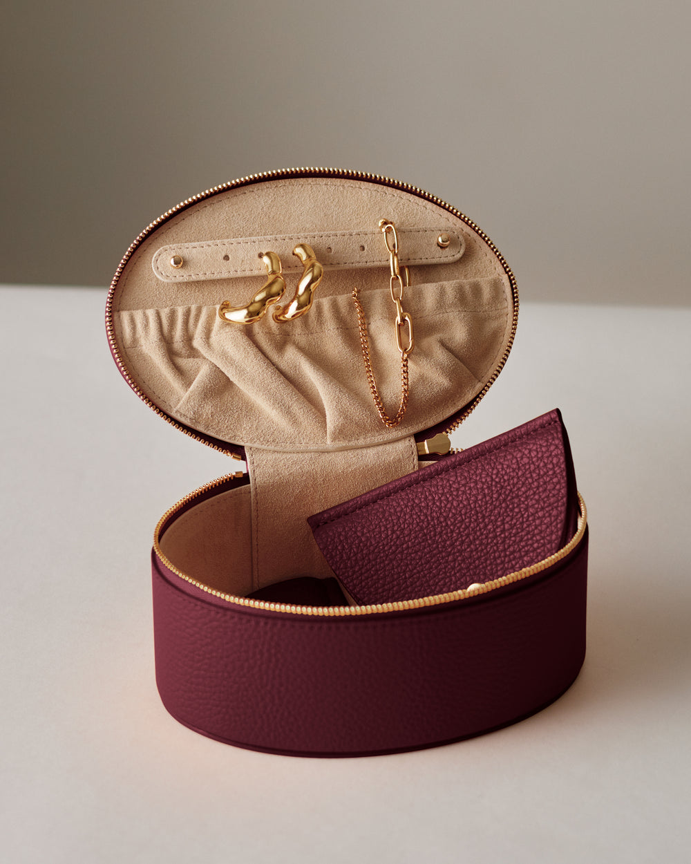 Round jewelry case with earrings and a necklace inside.