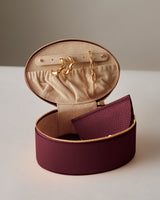 Round jewelry case with earrings and a necklace inside.