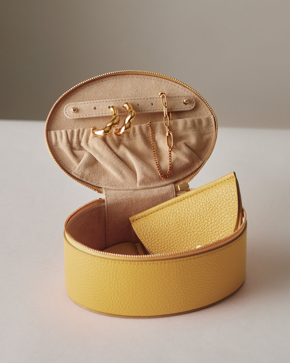 Round jewelry box with earrings and a chain inside.