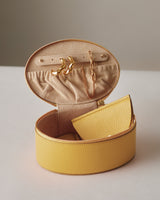 Round jewelry box with earrings and a chain inside.