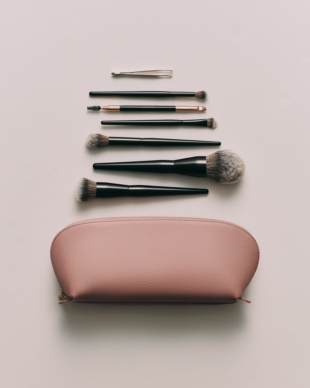 Makeup brushes and tools arranged above a cosmetic pouch.