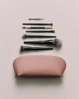 Makeup brushes and tools arranged above a cosmetic pouch.