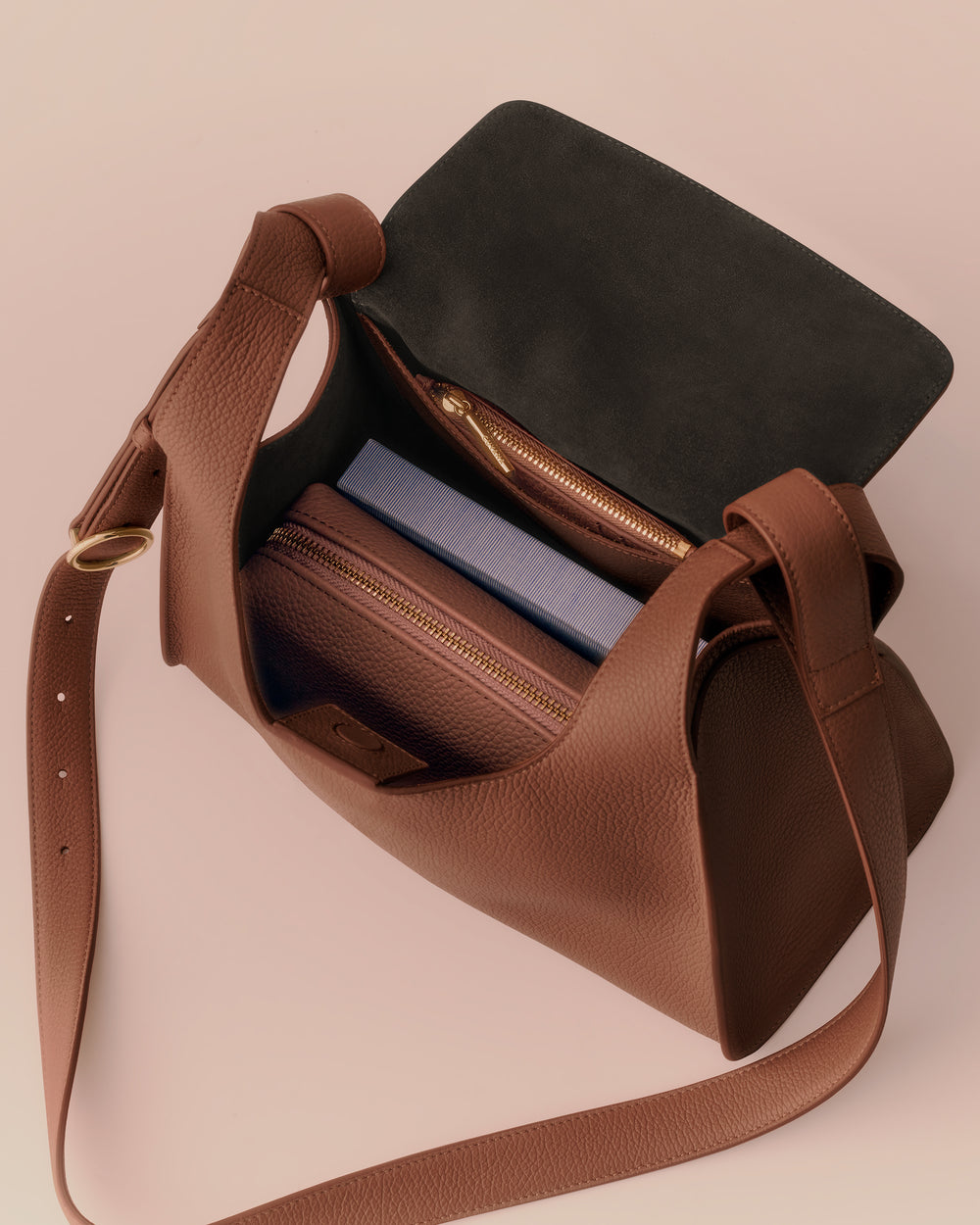 Open handbag with visible contents including a notebook and zippered pouch.