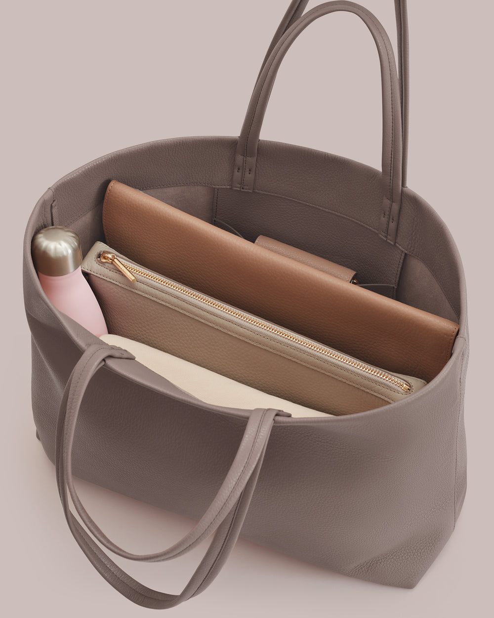 Open tote bag with a bottle and multiple pouches inside.
