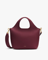 Handbag with a curved handle and detachable strap.