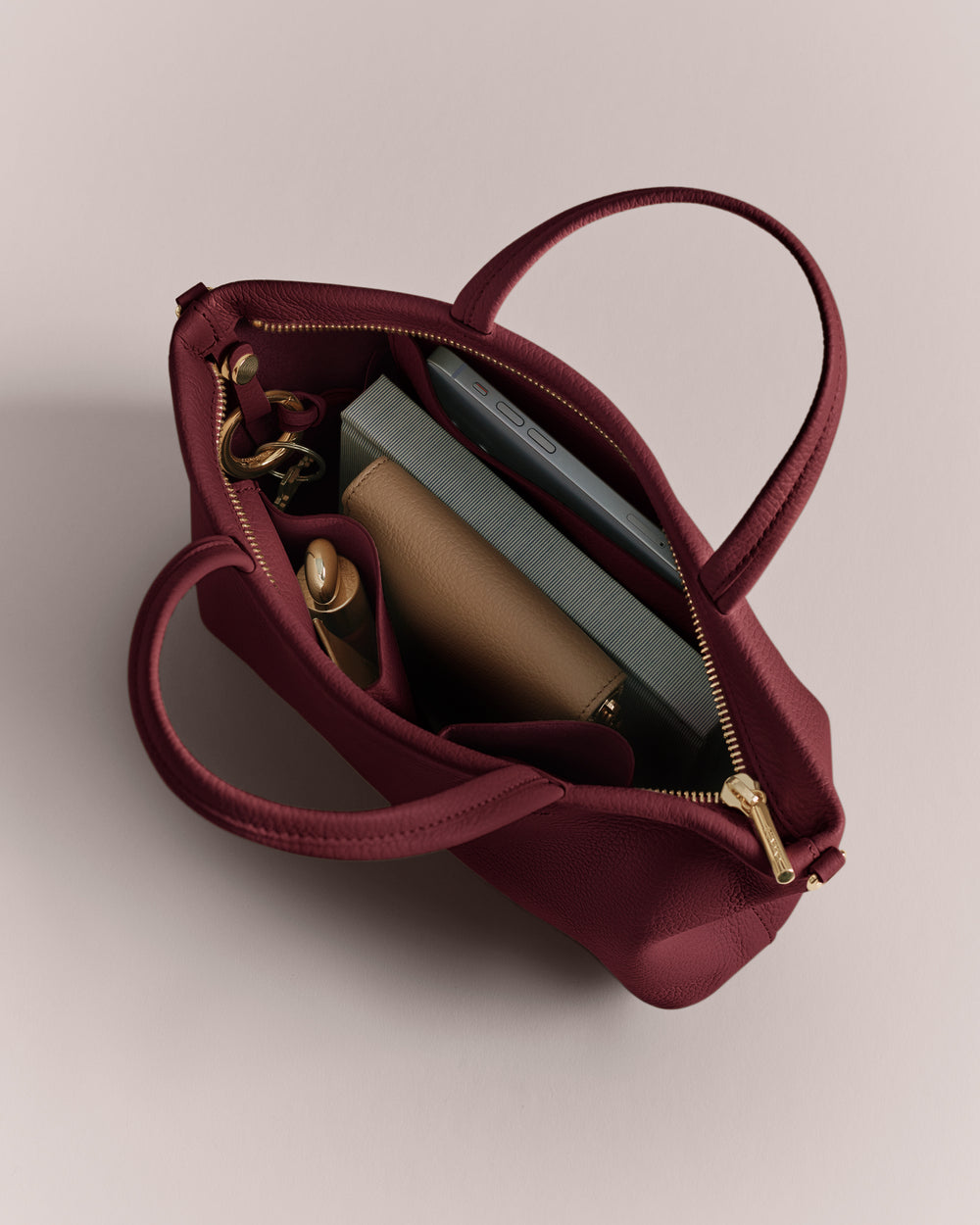 Open handbag with book, sunglasses, and water bottle inside.