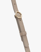 Close-up of a textured strap with a circular metal buckle.
