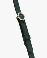 Bag strap with gold circular buckle on a plain background