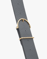 Belt with textured surface and a shiny metal buckle.