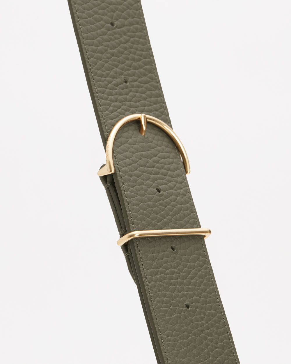 Close-up of a textured belt with a gold buckle and loop.