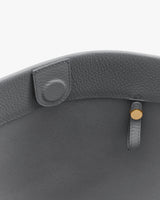 Open top view of a textured bag with a strap and clasp detail.