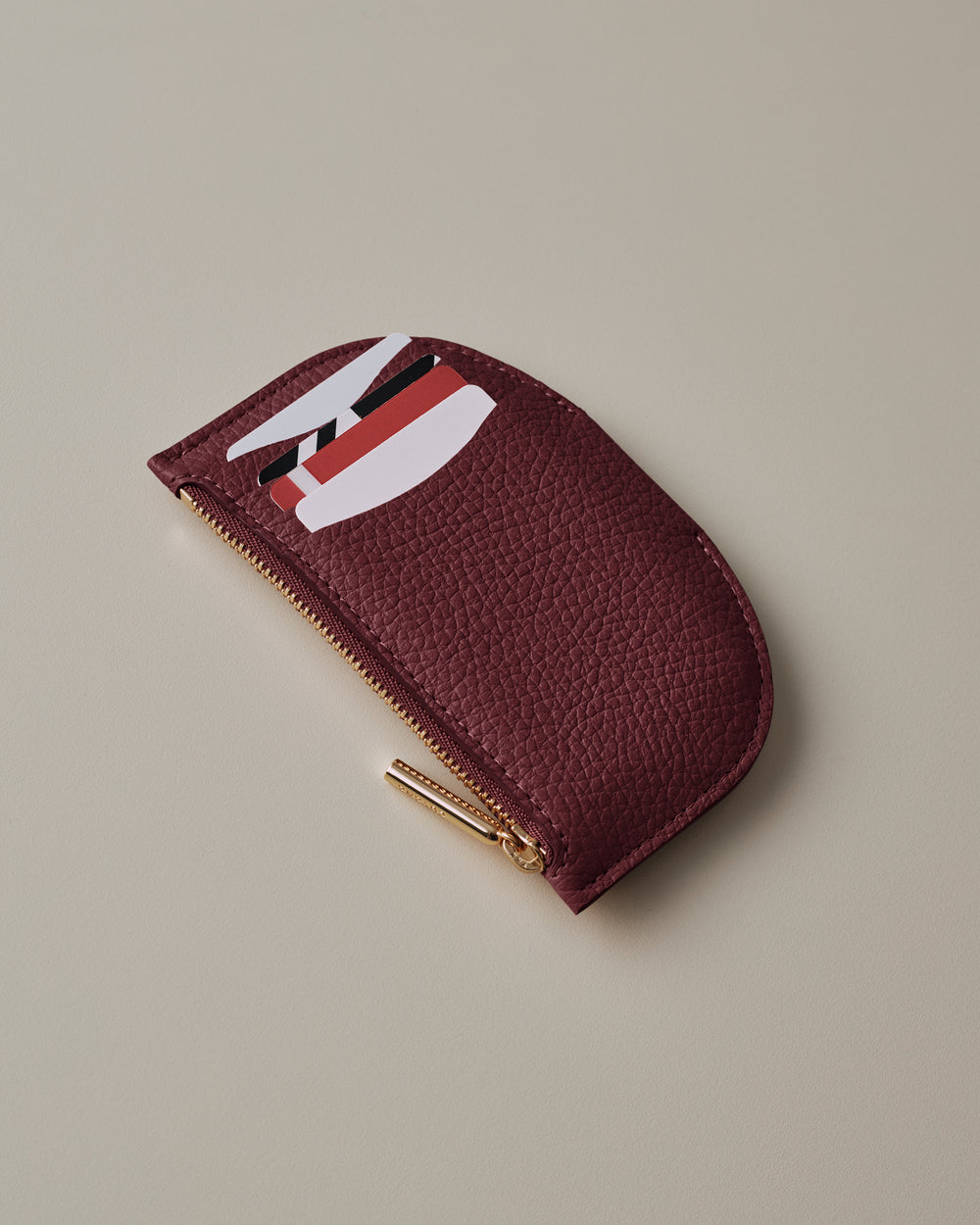 Half-circle zippered coin pouch with cards partially visible.