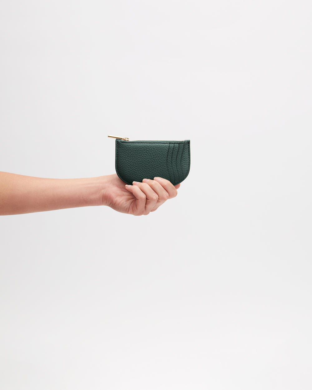 Hand holding a small zippered leather pouch against a plain background.
