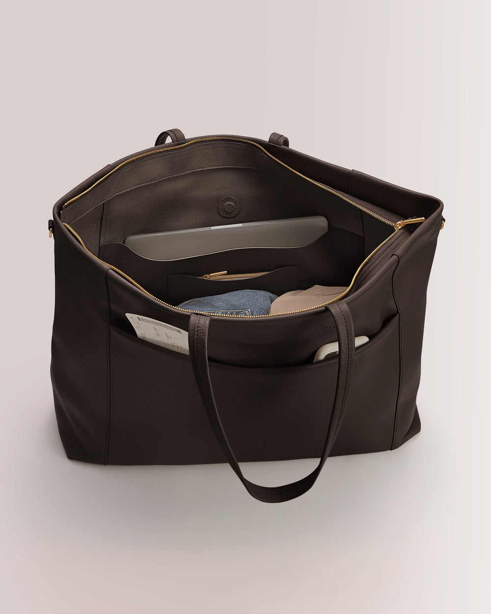 Large open tote bag with clothes and papers inside