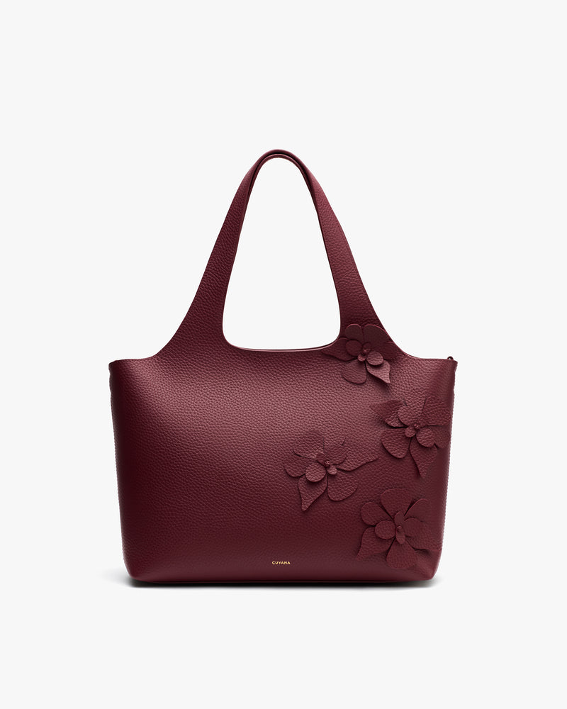 Handbag with floral details on upper corner and handles.