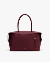 Handbag with curved handles and zipper closure on flat surface