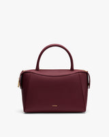 Handbag with a curved handle and zipper closure.