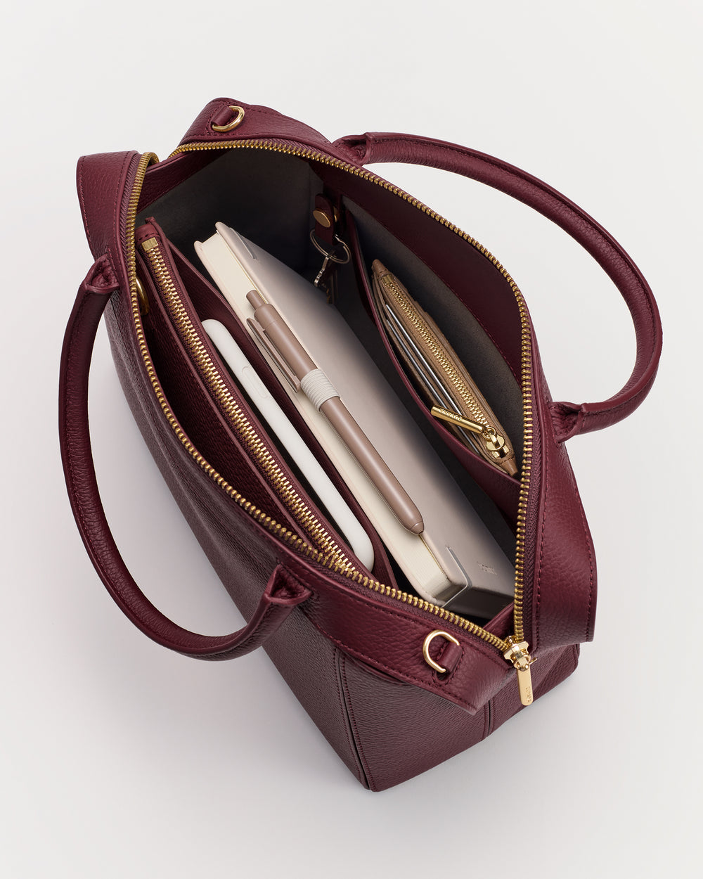 Open tote bag with notebook, pen, and zippered compartments inside.