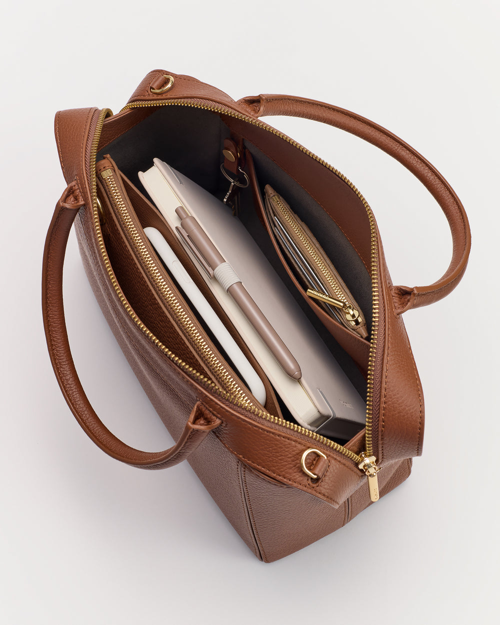 Open tote bag with a notebook, pen, and zippered pouch inside.