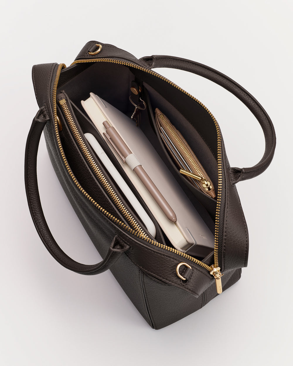 Open handbag with visible contents including a notebook, pen, and wallet.