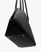 Handbag with four round studs on the bottom and long handles