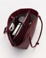 Open handbag with books, smartphone, and a small bottle inside.