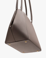Handbag with four metal feet and two handles.