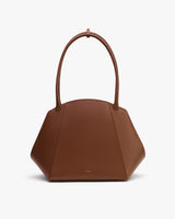 Handbag with rounded geometric shape and short handles.