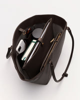 Open tote bag with phone, book, notebook, pen inside and straps visible.