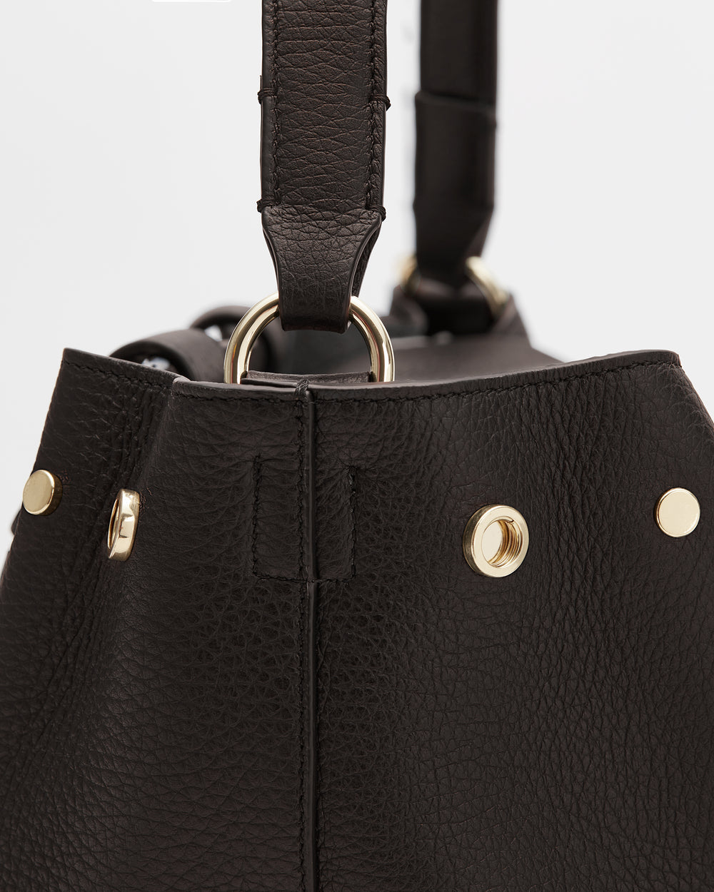 Close-up of a textured bag with metal ring and stud details.