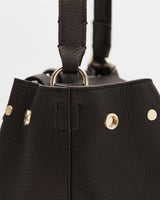 Close-up of a textured bag with metal ring and stud details.