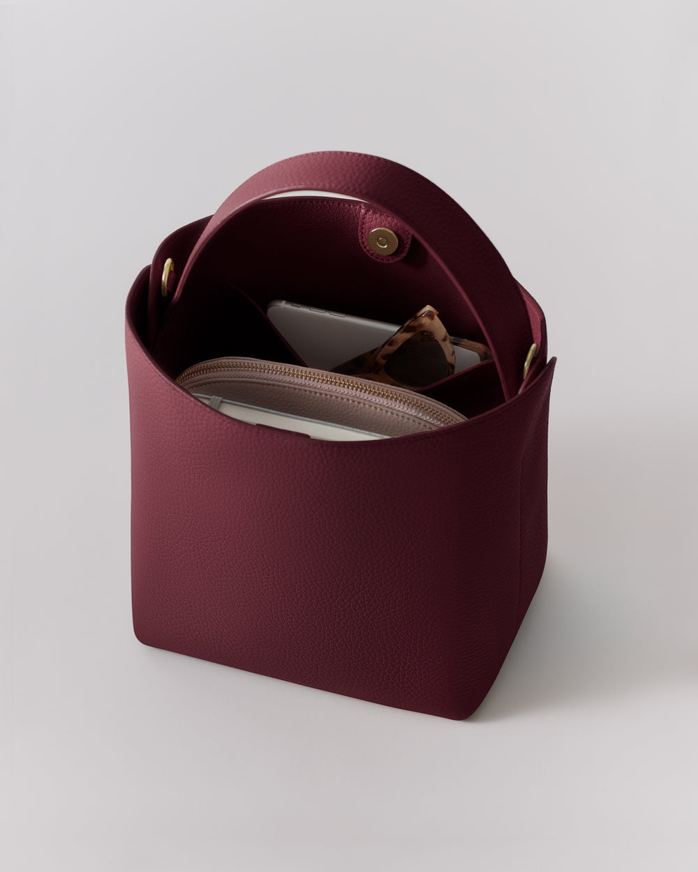 Open handbag showing a small pouch, smartphone, and sunglasses inside.
