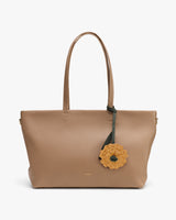 Tote bag with flower accessory attached to handle.