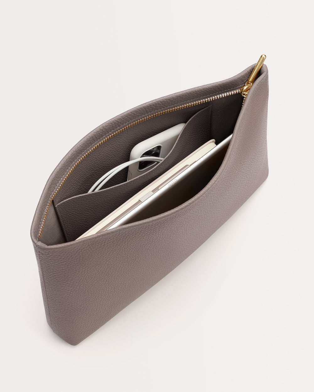 Clutch with phone and accessories inside open zippered pocket.