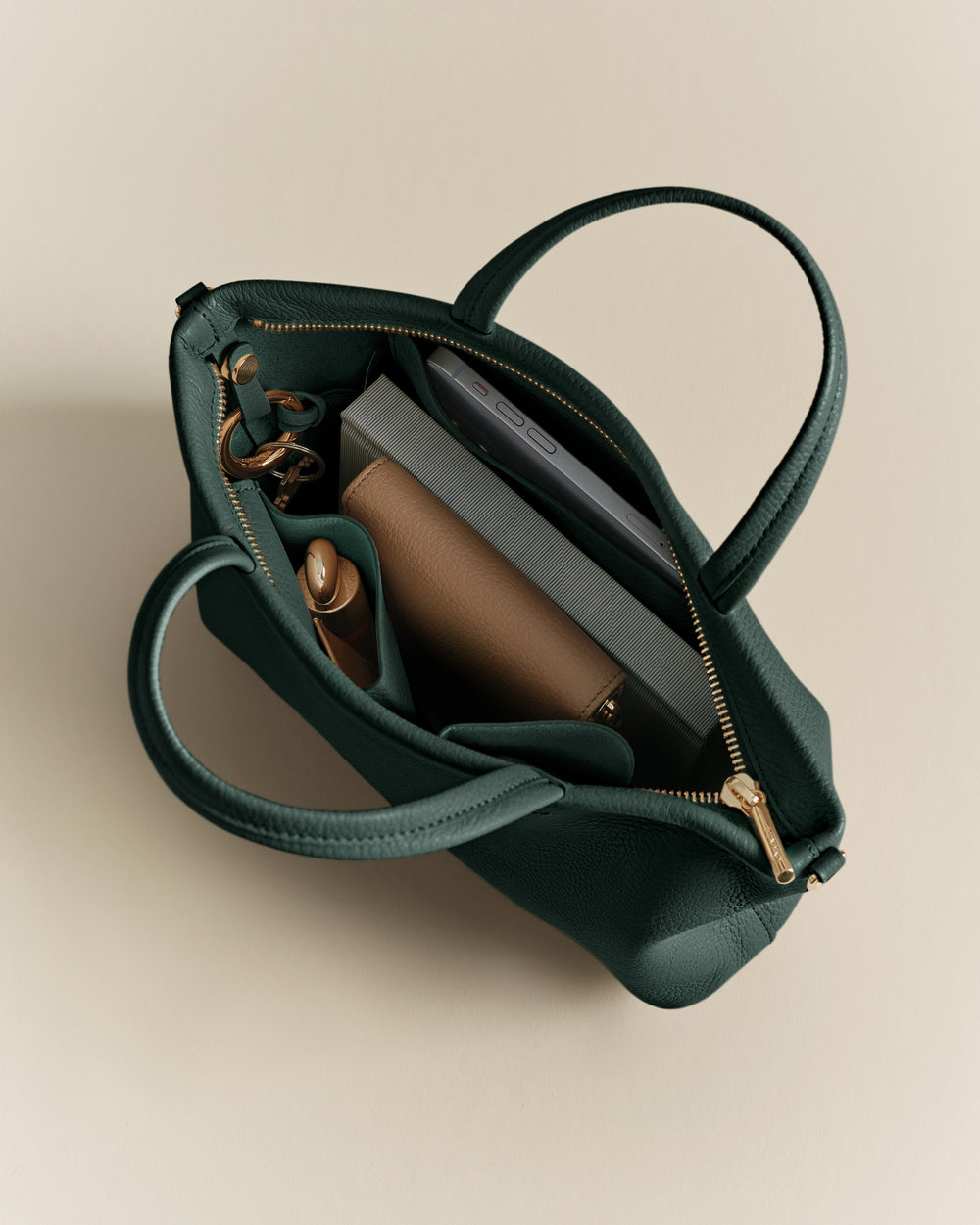 Open handbag with items like a wallet, book, and a phone inside