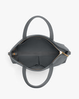 Top view of an open handbag with short handles and an interior zipper pocket.